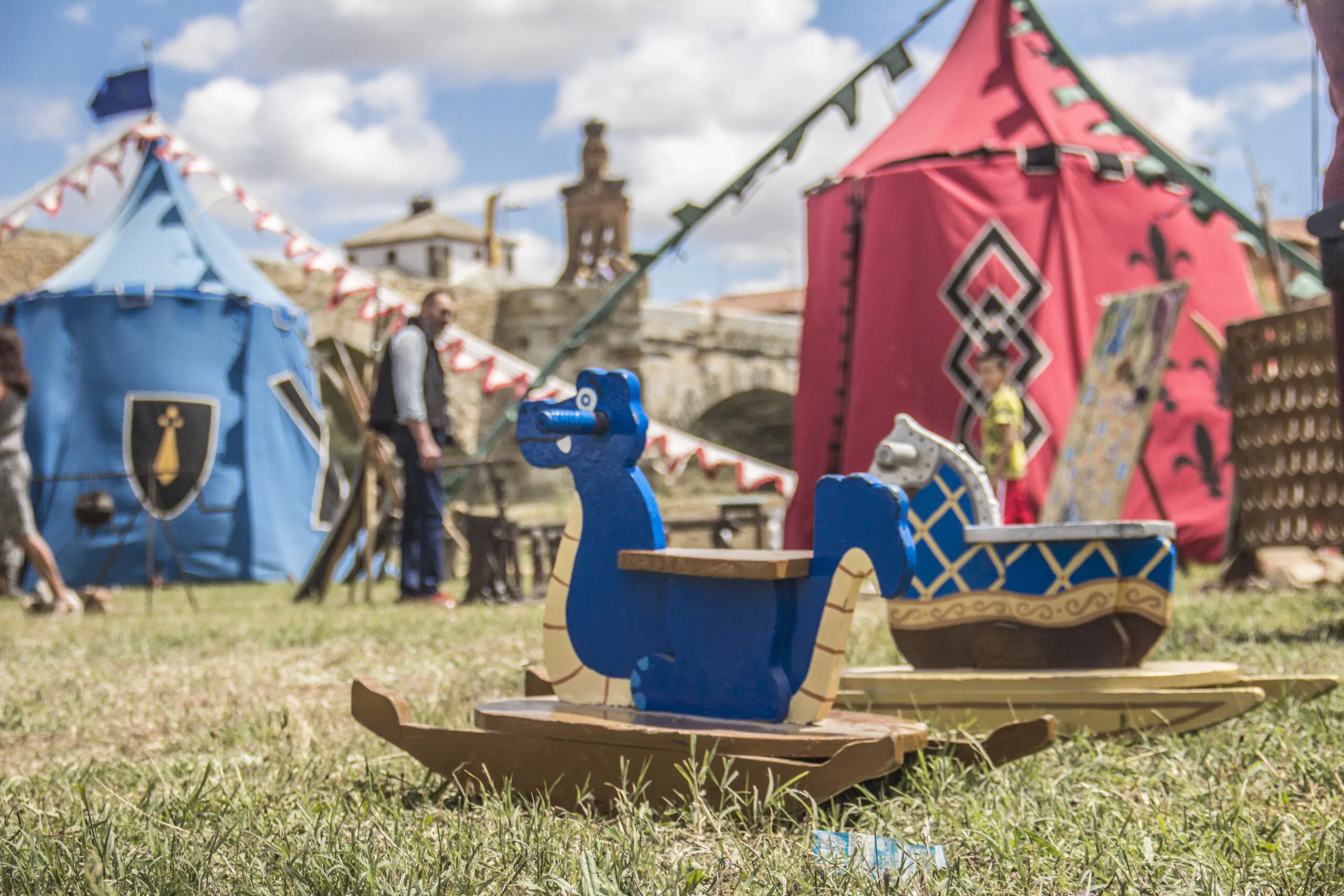 Juguetes de dragón y caballo en un campamento medieval al aire libre, con tiendas coloridas y decoraciones históricas